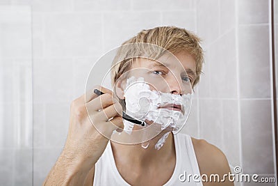 Portrait of mid-adult man shaving in bathroom