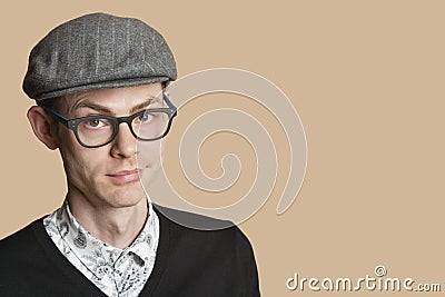 Portrait of a mid adult man wearing retro glasses and cap over colored background