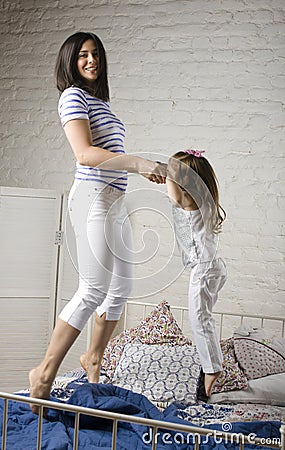 Portrait of mother and daughter laying in bed and smiling