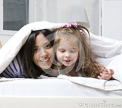Portrait of mother and daughter laying in bed and smiling