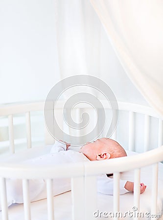 Portrait of a newborn baby boy in white round crib