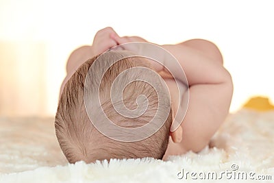 Portrait of a newborn baby lying on bed with back of head