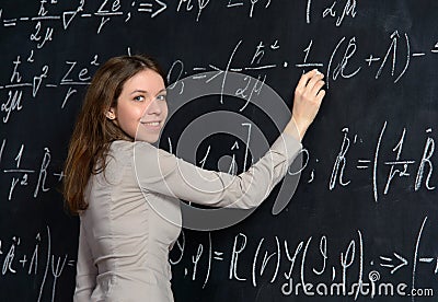 Portrait of a pretty student doing maths on a blackboard