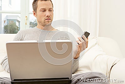 Portrait of professional man with laptop and smart phone at home.