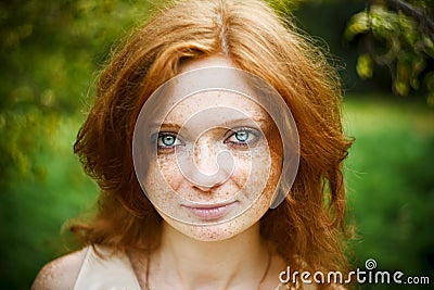 Portrait of redhead girl with blue eyes on nature