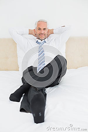 Portrait of a relaxed mature businessman sitting in bed