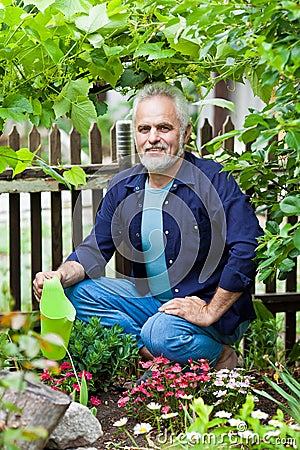 Portrait of senior man watering flowers