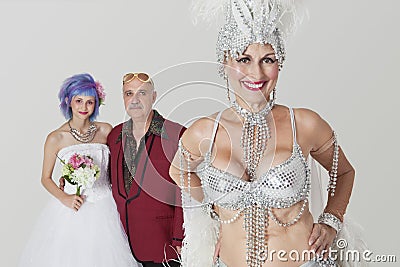 Portrait of senior showgirl with father and daughter in wedding dress in background
