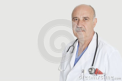 Portrait of serious senior medical practitioner with stethoscope over gray background