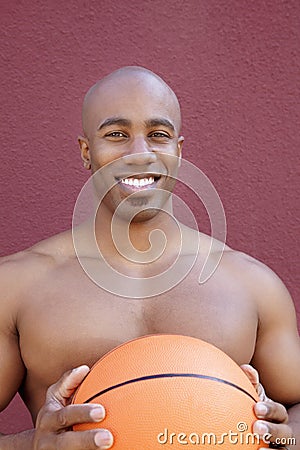 Portrait of a shirtless African American man with basketball over colored background