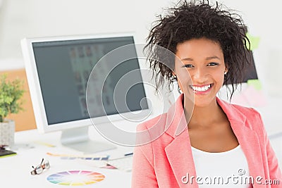 Portrait of a smiling female artist at desk with computer