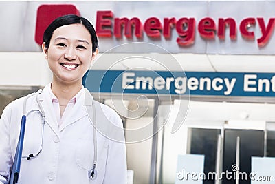 Portrait of smiling female doctor outside of the hospital, emergency room sign in the background