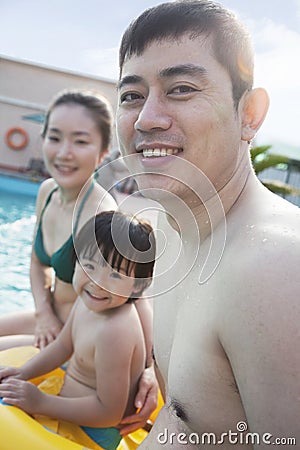 Portrait of smiling happy family sitting by the pool