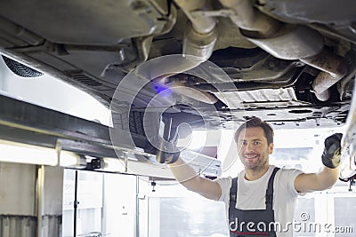 Portrait of smiling repair worker examining car in workshop