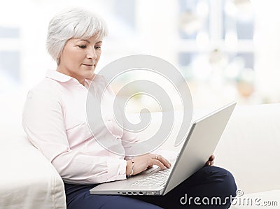 Smiling senior woman working on laptop