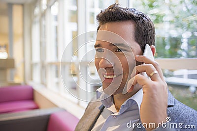 Portrait of a smiling young businessman using cellphone on sofa,