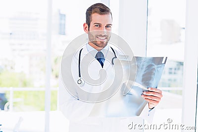 Portrait of a smiling young male doctor examining xray