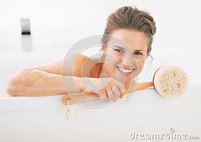 Portrait of smiling young woman holding body brush