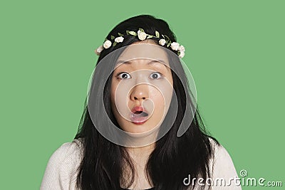 Portrait of a surprised young woman over green background