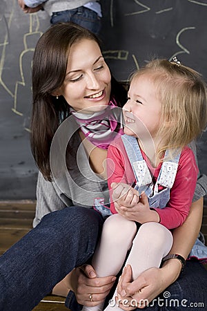 Portrait of teacher and little student, mother and daughter near blackboard