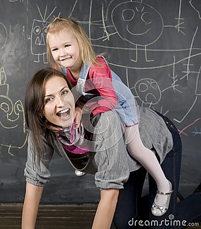 Portrait of teacher and little student, mother and daughter near blackboard