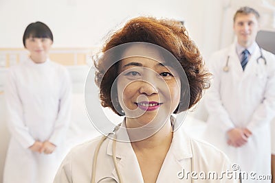 Portrait of three smiling doctors, female doctor at the front