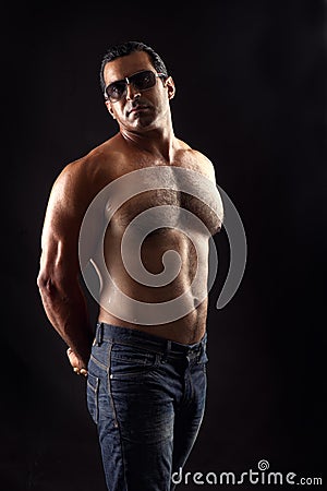 Portrait of topless athletic man posing over black