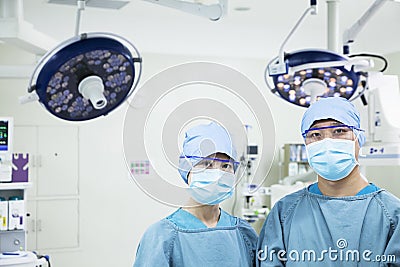 Portrait of two surgeons wearing surgical masks in the operating room, looking at camera