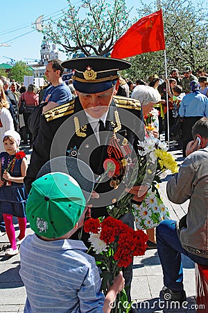 Portrait of a war veteran receiving flowers from a boy.