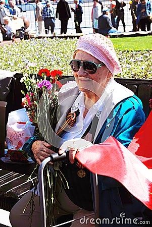 Portrait of a war veteran woman smiling holding flowers buds.