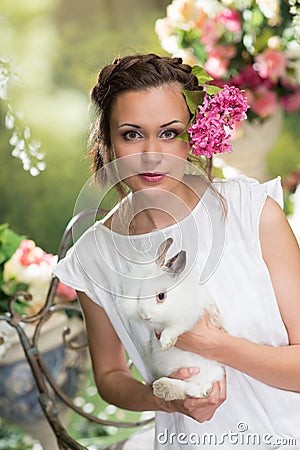 Portrait of woman with white rabbit. Green floral garden