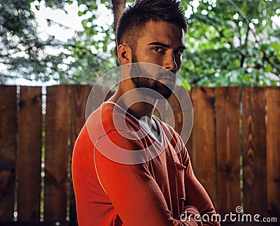 Portrait of young beautiful man in orange, against outdoor background.