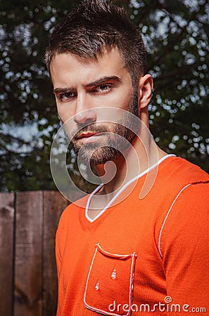 Portrait of young beautiful man in orange, against outdoor background.