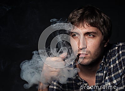 Portrait of the young beautiful man smoking a pipe