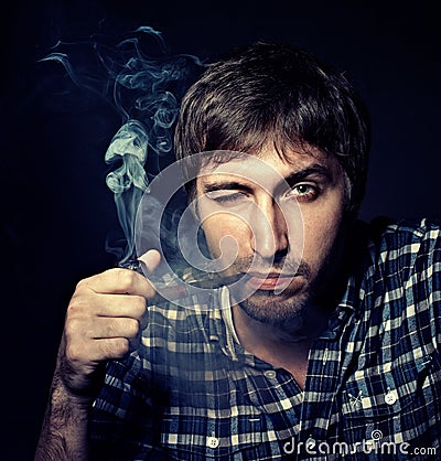 Portrait of the young beautiful man smoking a pipe