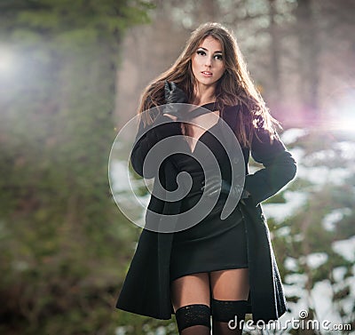 Portrait of young beautiful woman outdoor in winter scenery. Sensual brunette with long legs in black stockings posing fashionable