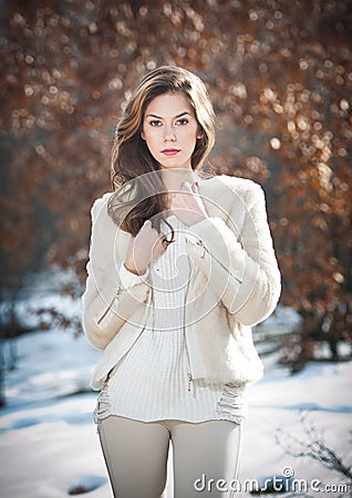 Portrait of young beautiful woman wearing white clothes outdoor. Beautiful brunette girl with long hair posing outdoor in winter