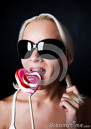 Portrait of young blond woman eating candy