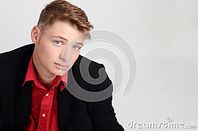 Portrait of a young business man wearing a black suit and a red shirt. Man looking up.