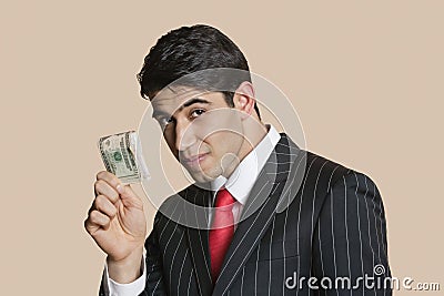 Portrait of a young businessman showing paper money over colored background