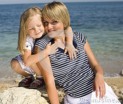 Portrait of young family having fun on the beach, mother and daughter at sea