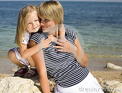 Portrait of young family having fun on the beach, mother and daughter at sea