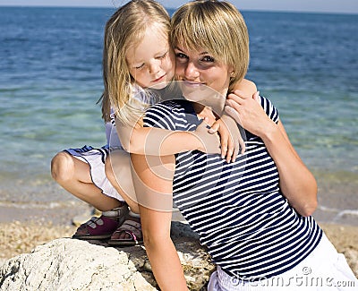 Portrait of young family having fun on the beach, mother and daughter at sea