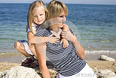 Portrait of young family having fun on the beach, mother and daughter at sea