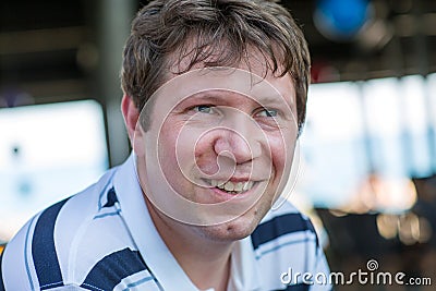 Portrait of young man smiling and sitting in summer restaurant