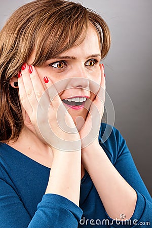 Portrait of young surprised girl holding her face and smiling