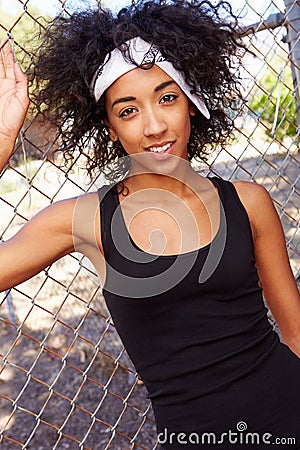 Portrait Of Young Woman In Urban Setting Standing By Fence