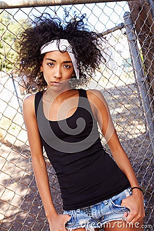 Portrait Of Young Woman In Urban Setting Standing By Fence