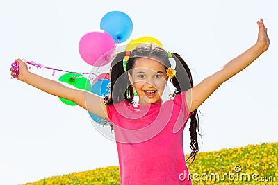 Positive girl with arms up and balloons in air