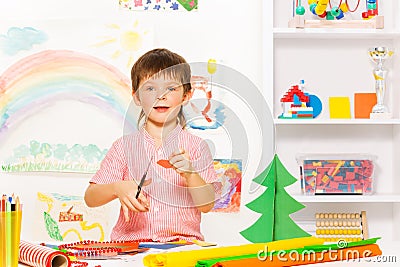 Positive small boy holding scissors and carton